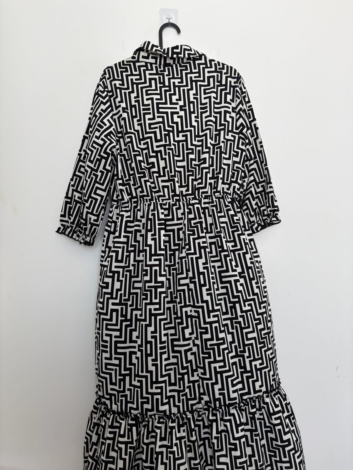 The Circle black and white geometric print midi dress with a button-down front, tiered ruffle hem, and 3/4 sleeves.