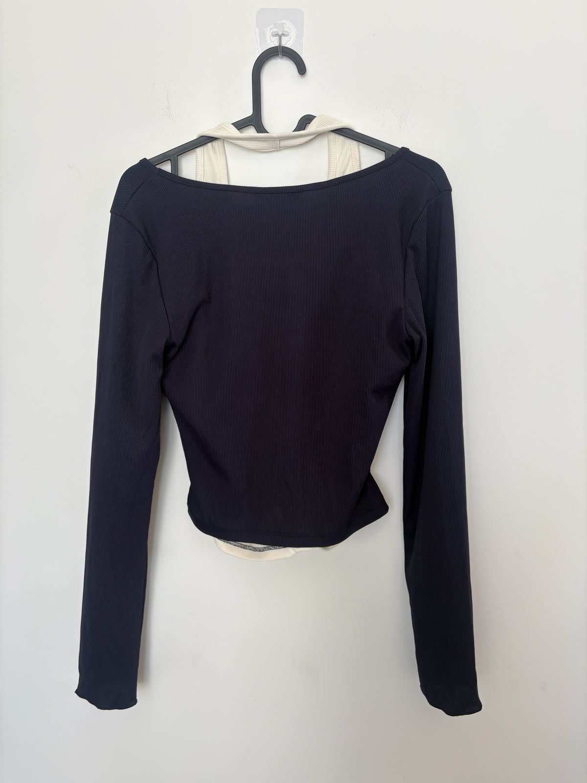 The Circle layered long sleeve crop top in black and cream ribbed fabric with a two-in-one shrug and tank design.