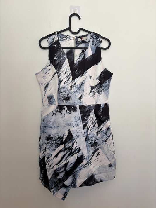 The Circle sleeveless mini dress featuring a monochrome geometric marble print, V-neckline, and asymmetrical hem.