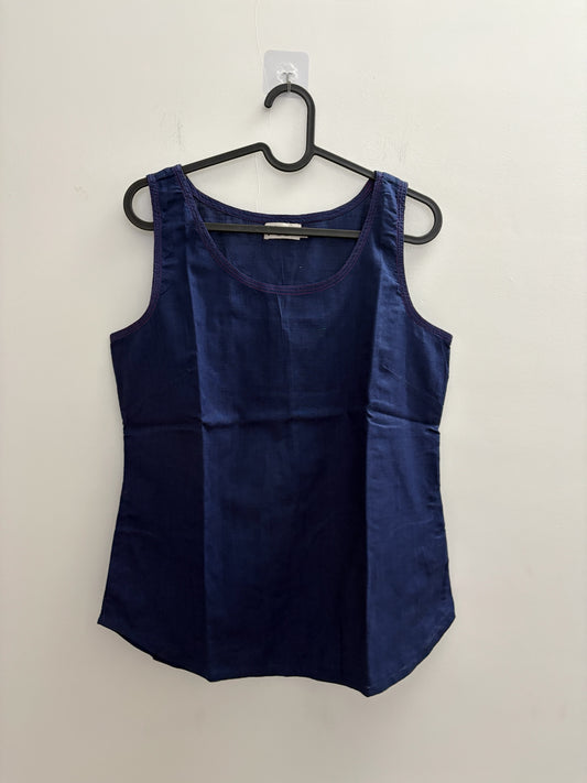 The Circle navy blue sleeveless cotton tank top with a scoop neckline and contrast stitch detailing on a hanger.