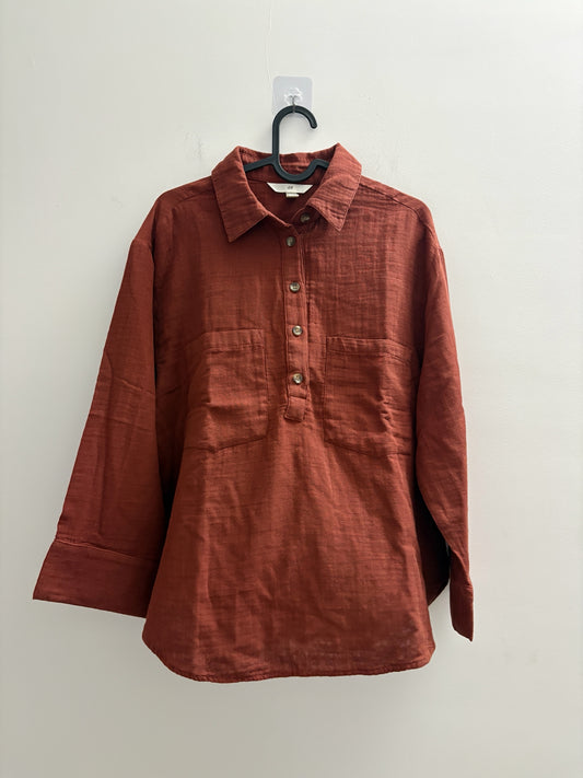 The Circle rust-coloured long sleeve button-down shirt with a textured finish, collar, and two chest pockets.