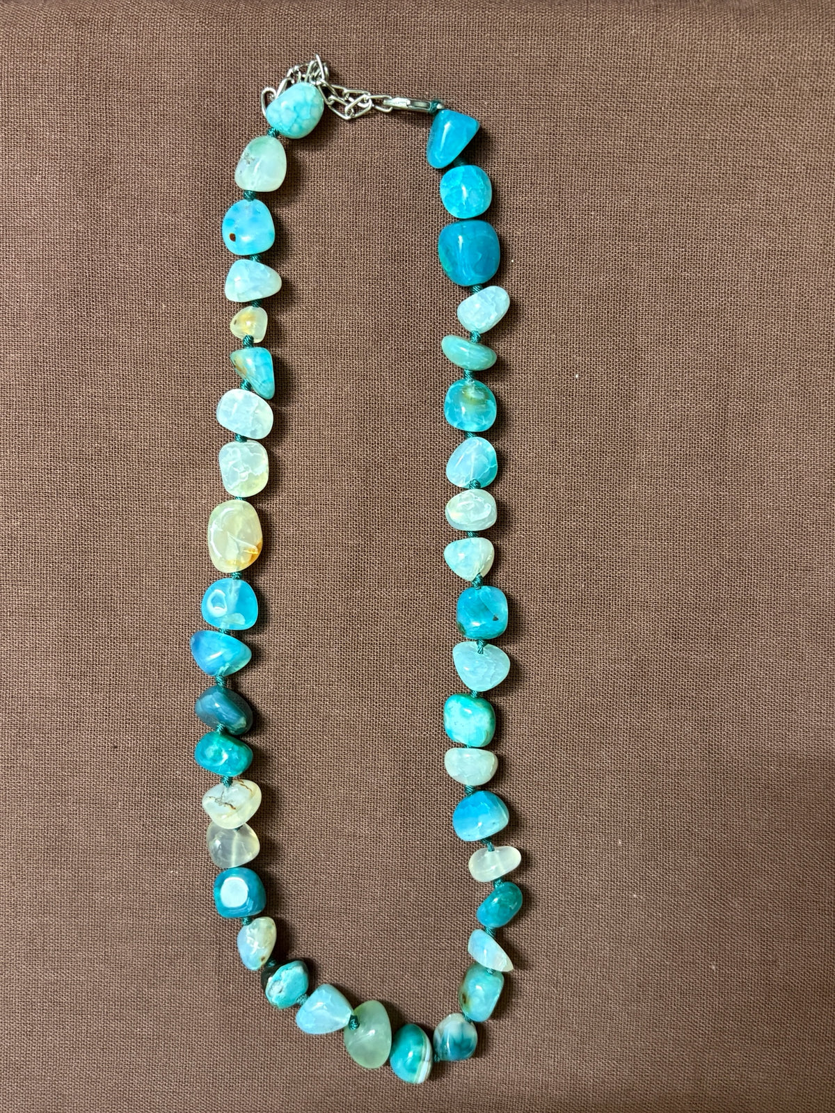 The Circle handcrafted necklace featuring polished blue agate stones in shades of turquoise and aquamarine with a silver clasp