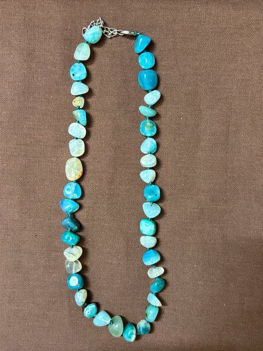 The Circle handcrafted necklace featuring polished blue agate stones in shades of turquoise and aquamarine with a silver clasp