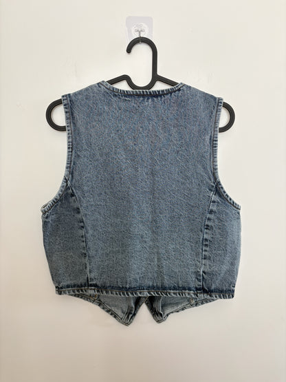 The Circle sleeveless washed-blue denim waistcoat featuring a tailored back view on a black hanger.