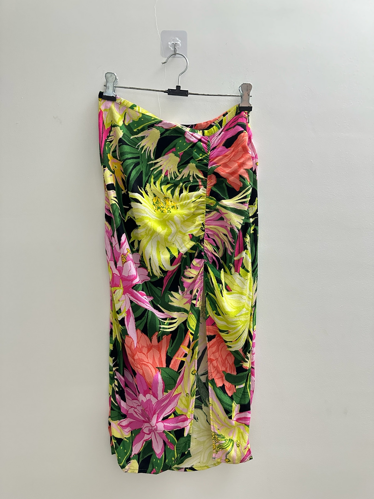 The Circle floral midi skirt featuring a black base with vibrant yellow, pink, and coral botanical print and side ruching