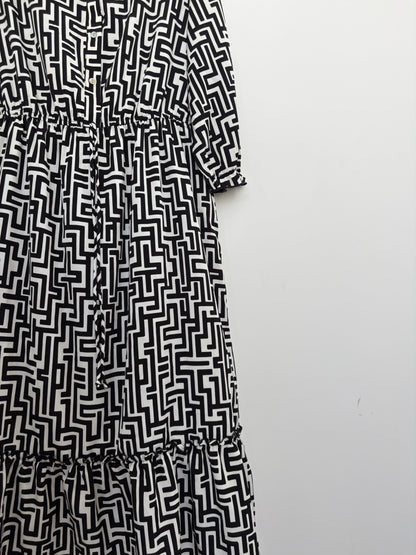 The Circle black and white geometric print midi dress with a button-down front, elasticated waist, and tiered hem.