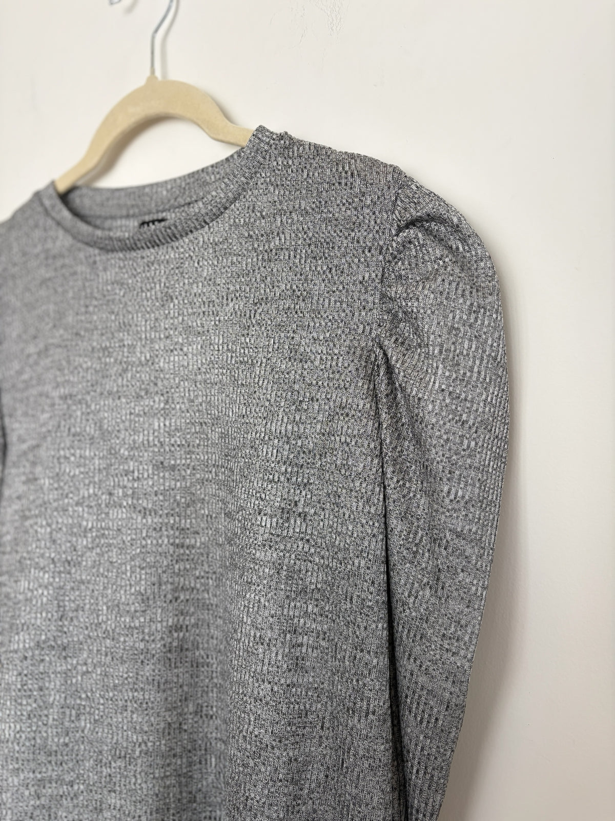 The Circle grey knit pullover top featuring a crew neckline and dramatic puff sleeves on a hanger.