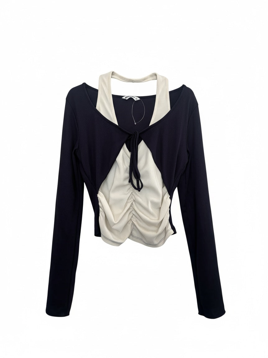 The Circle layered long sleeve crop top featuring a black shrug over a cream ruched tank with a front tie detail.