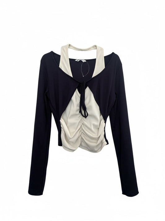 The Circle layered long sleeve crop top featuring a black shrug over a cream ruched tank with a front tie detail.