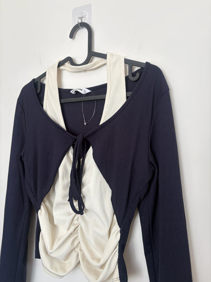 The Circle layered long sleeve crop top with a black shrug and cream ribbed ruched tank featuring a front tie detail.