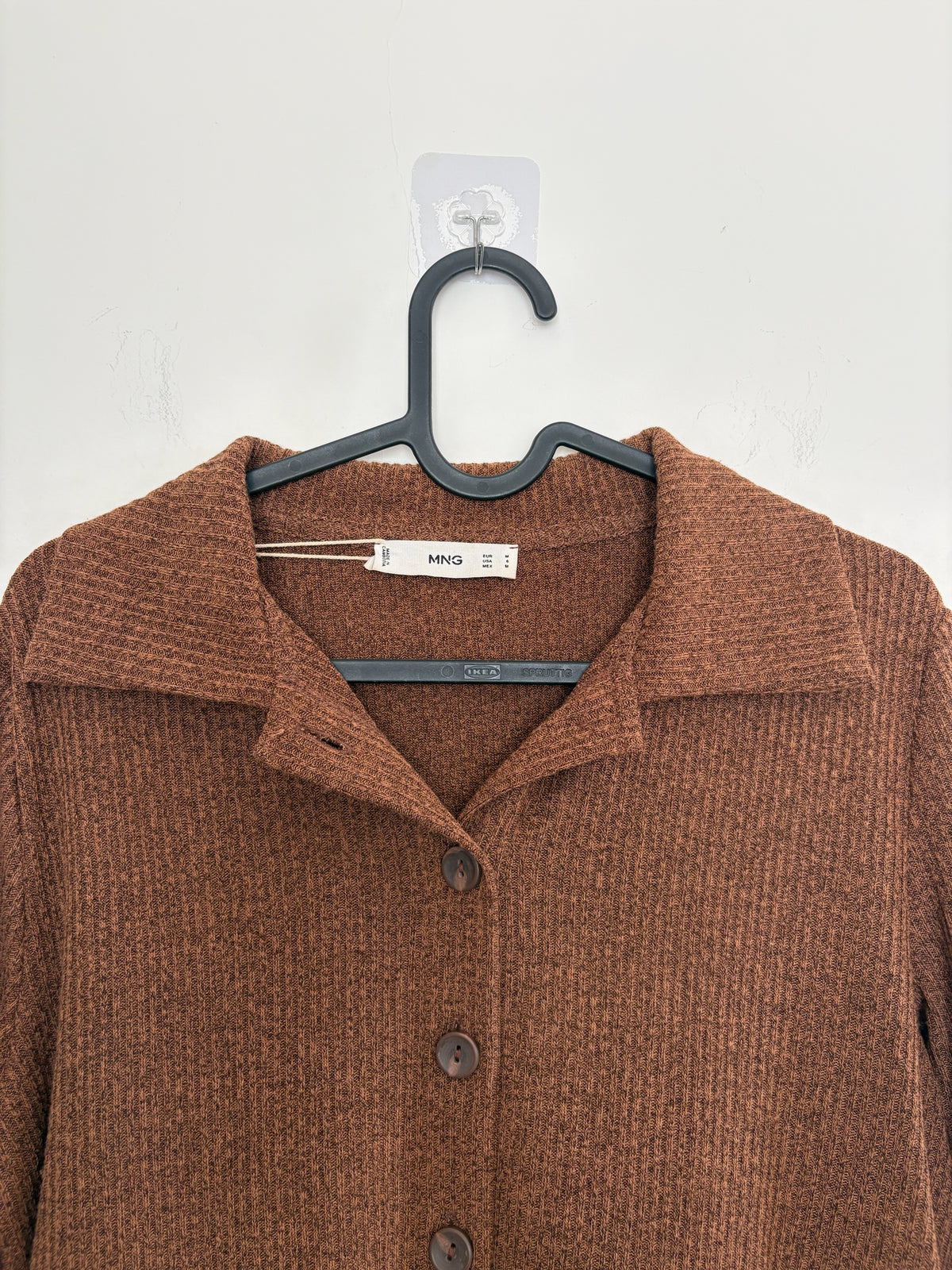 The Circle MNG brown ribbed knit button-down shirt with a classic polo collar hanging on a black hanger.