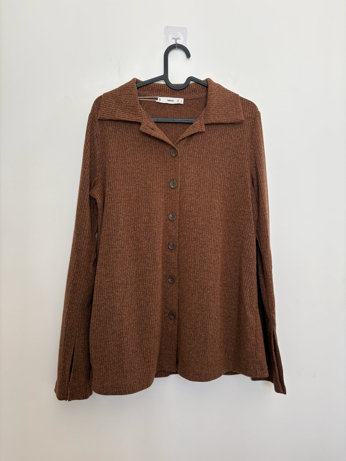 The Circle MNG brown ribbed knit button-down shirt with a polo collar and split-cuff sleeves hanging on a hanger.