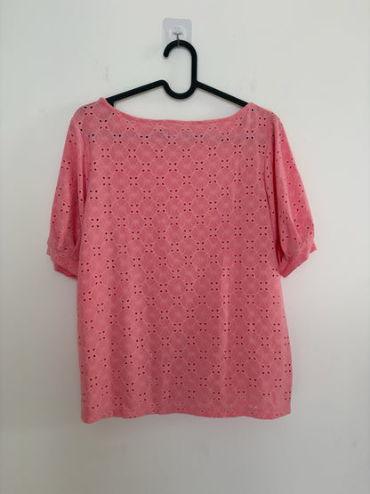 The Circle pink eyelet embroidered casual top with short puff sleeves and a round neckline hanging on a black hanger.