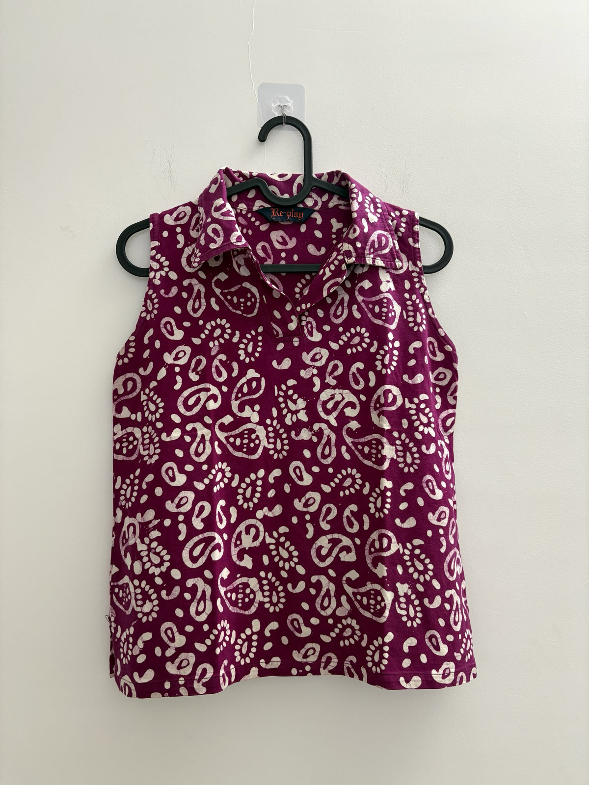 The Circle sleeveless polo top in deep purple with a white batik paisley print, featuring a structured collar.
