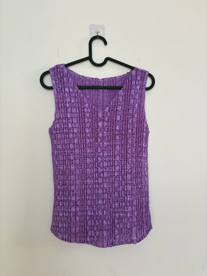 The Circle purple sleeveless V-neck top with a textured crinkle finish hanging on a black hanger against a white wall.