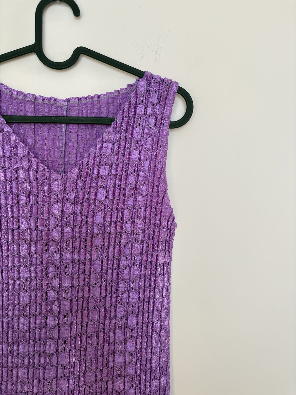 The Circle purple sleeveless V-neck top with a textured crinkle fabric finish hanging on a black hanger.