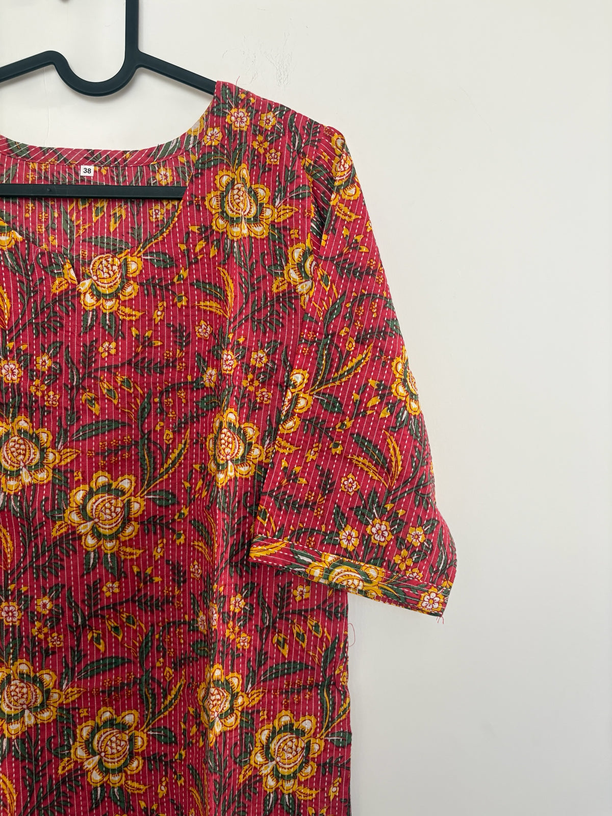 The Circle red cotton kurta featuring yellow and green floral block prints and delicate kantha-style vertical stitching.
