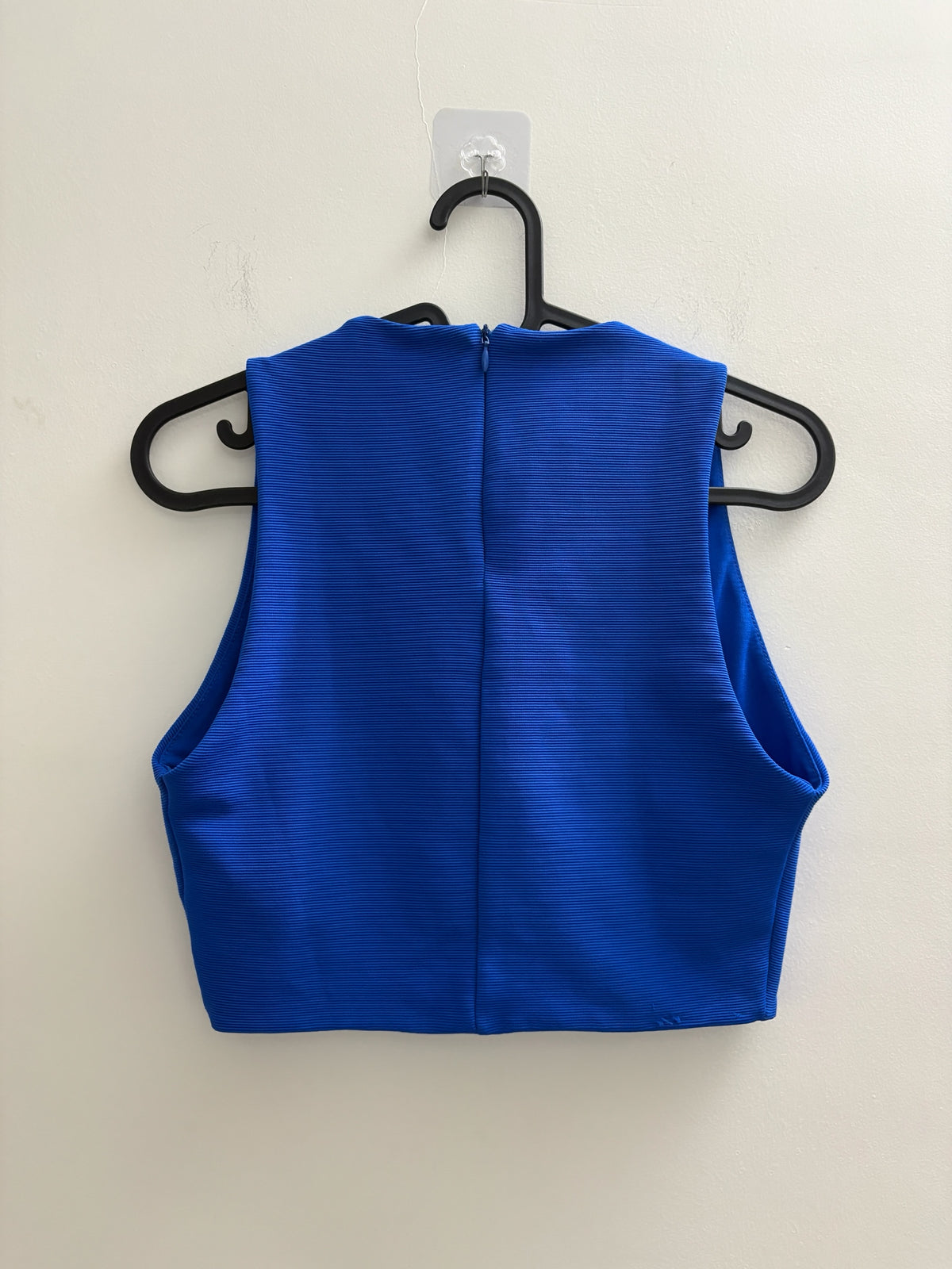 The Circle royal blue sleeveless cropped top with textured fabric and back zip closure hanging on a hanger
