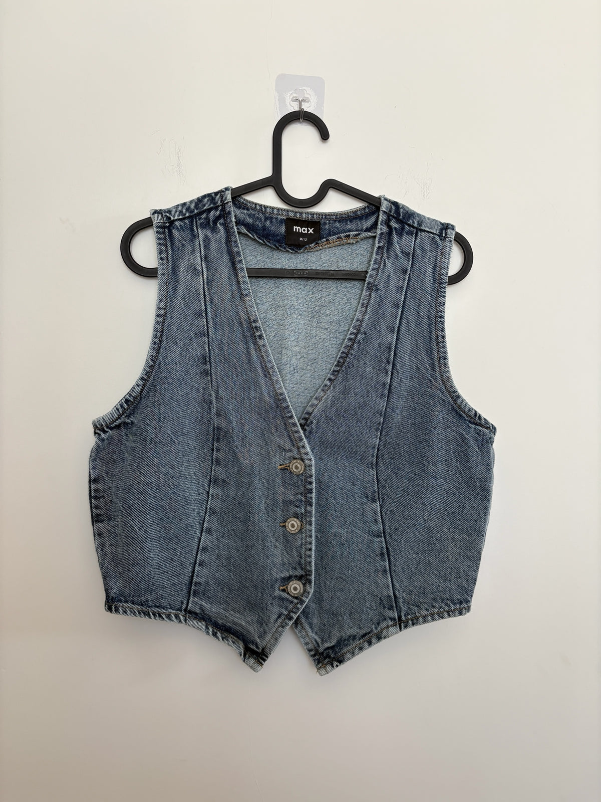 The Circle sleeveless washed-blue denim waistcoat with a V-neckline and button-down front on a black hanger