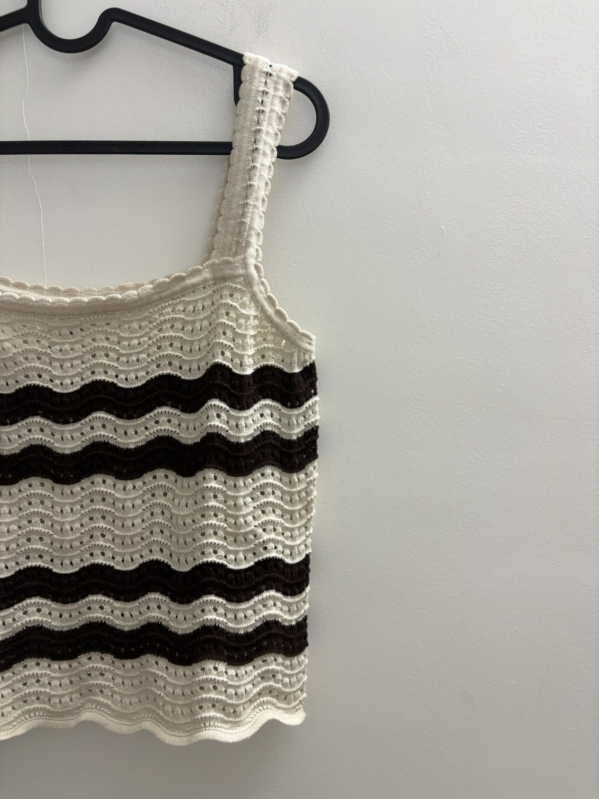 The Circle cream and dark brown striped crochet tank top with a square neckline and scalloped edges on a hanger.