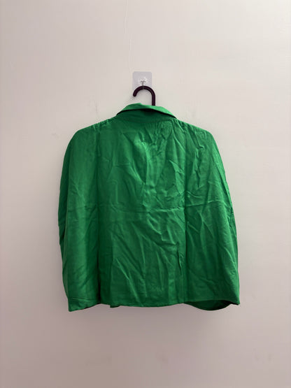The Circle ZUDIO emerald green sleeveless button-down shirt with a classic collar hanging against a white wall.